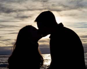 silhouette of couple kissing with ocean in the background